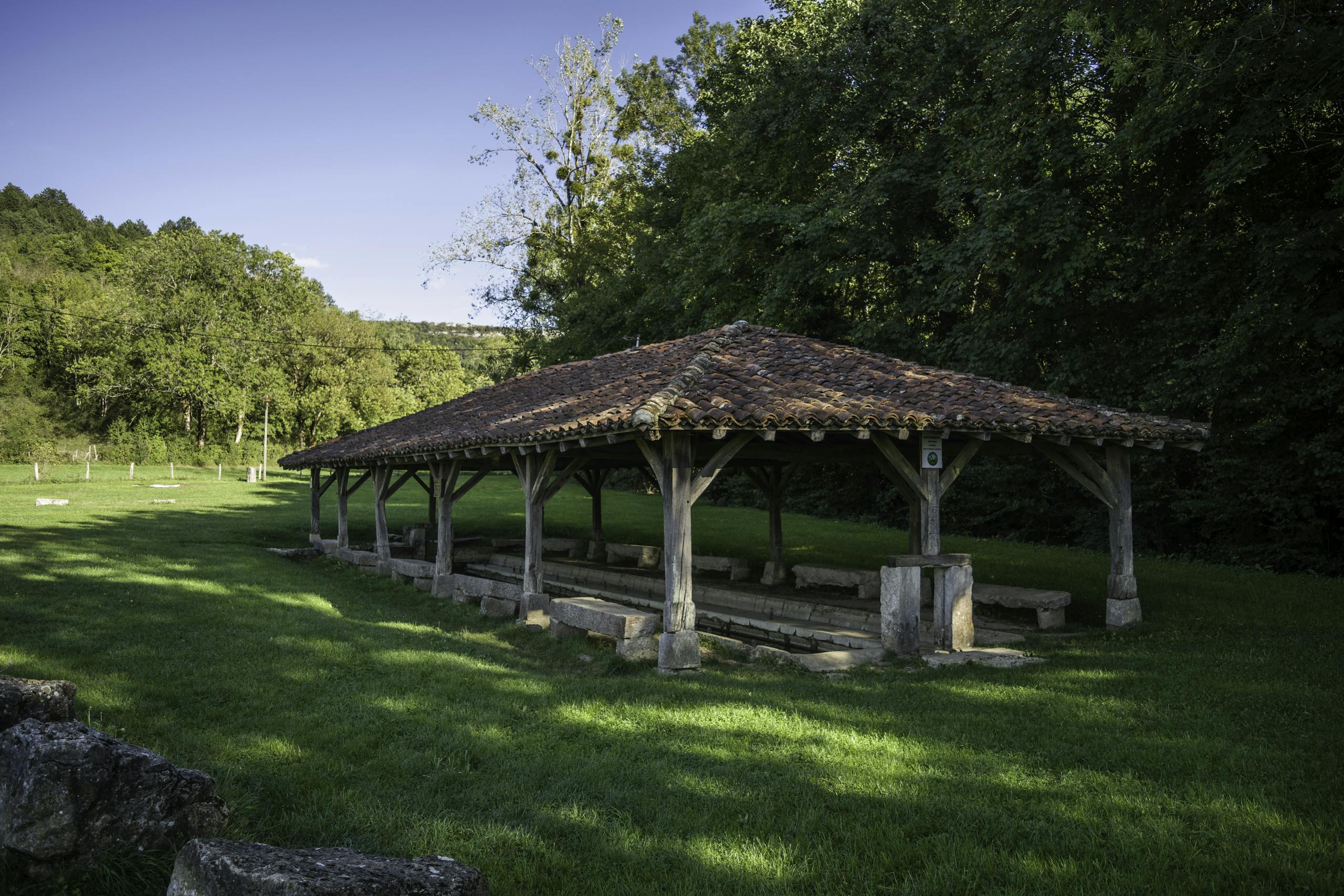 A historic lavoir set in the lush greenery of Val-Revermont, France, showcasing rural architecture.